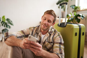 Voyageur qui consulte son téléphone comme tendance 2026 de la location courte durée pour échanger avec sa conciergerie airbnb